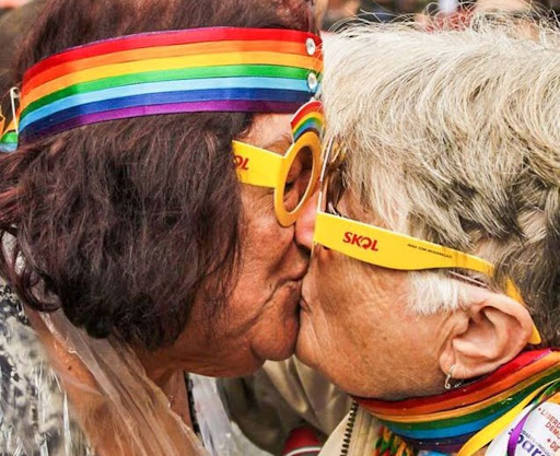 Casal de idosos LGBTQIAPN+ se beijando.